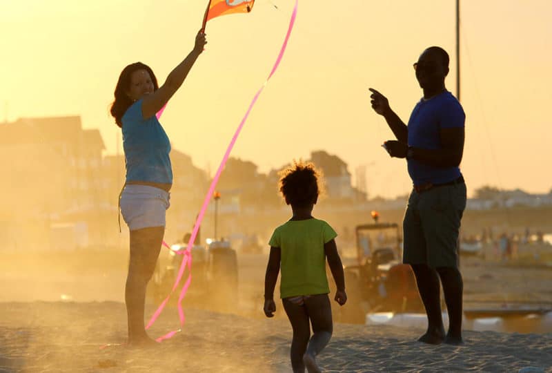 A family on the beach at sunset with a kite